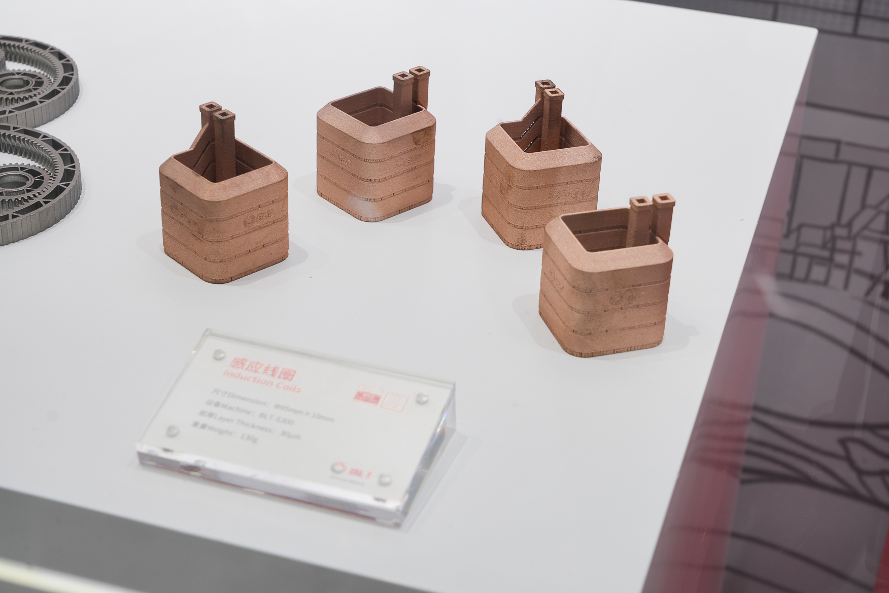 Four copper additive induction coil blanks on a white display surface