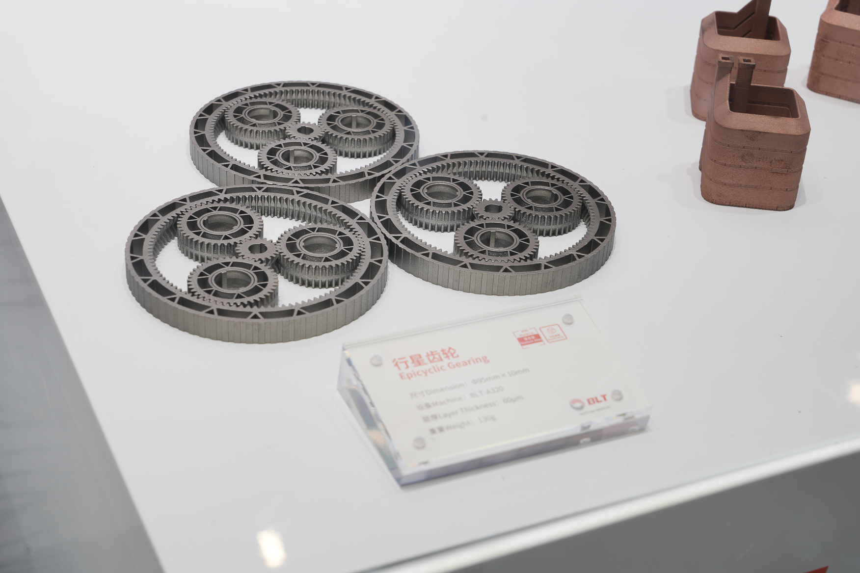 Three metal additive epicyclic planetary gear assemblies on a white surface