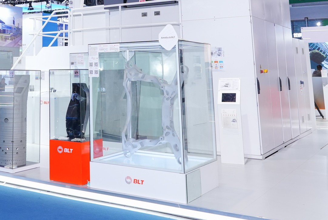 Metal additive automotive rear subframe blank displayed in a glass exhibit case