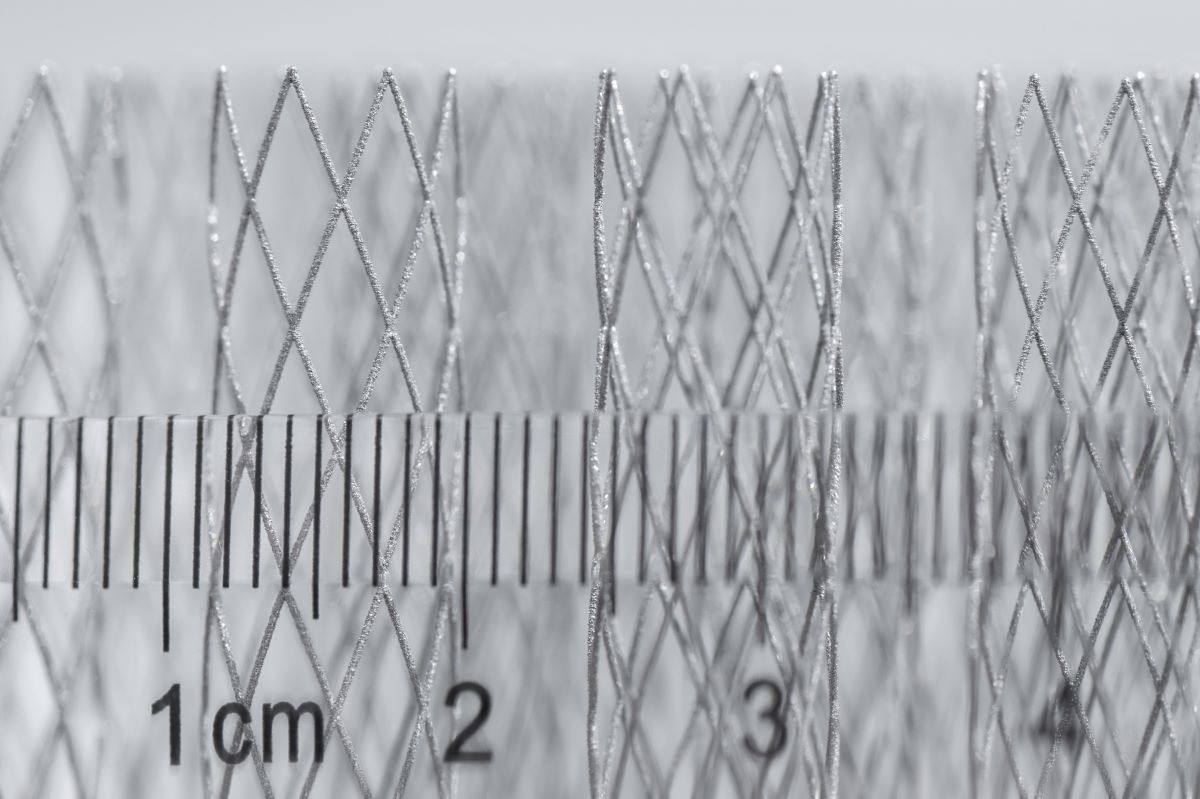 Batch of metal additive micro-lattice cylinders next to a centimeter scale ruler