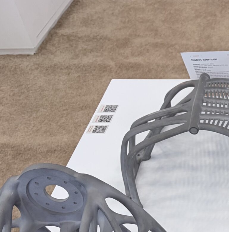 Metal additive robot sternum lattice blank displayed beside a parallel-rib coupon
