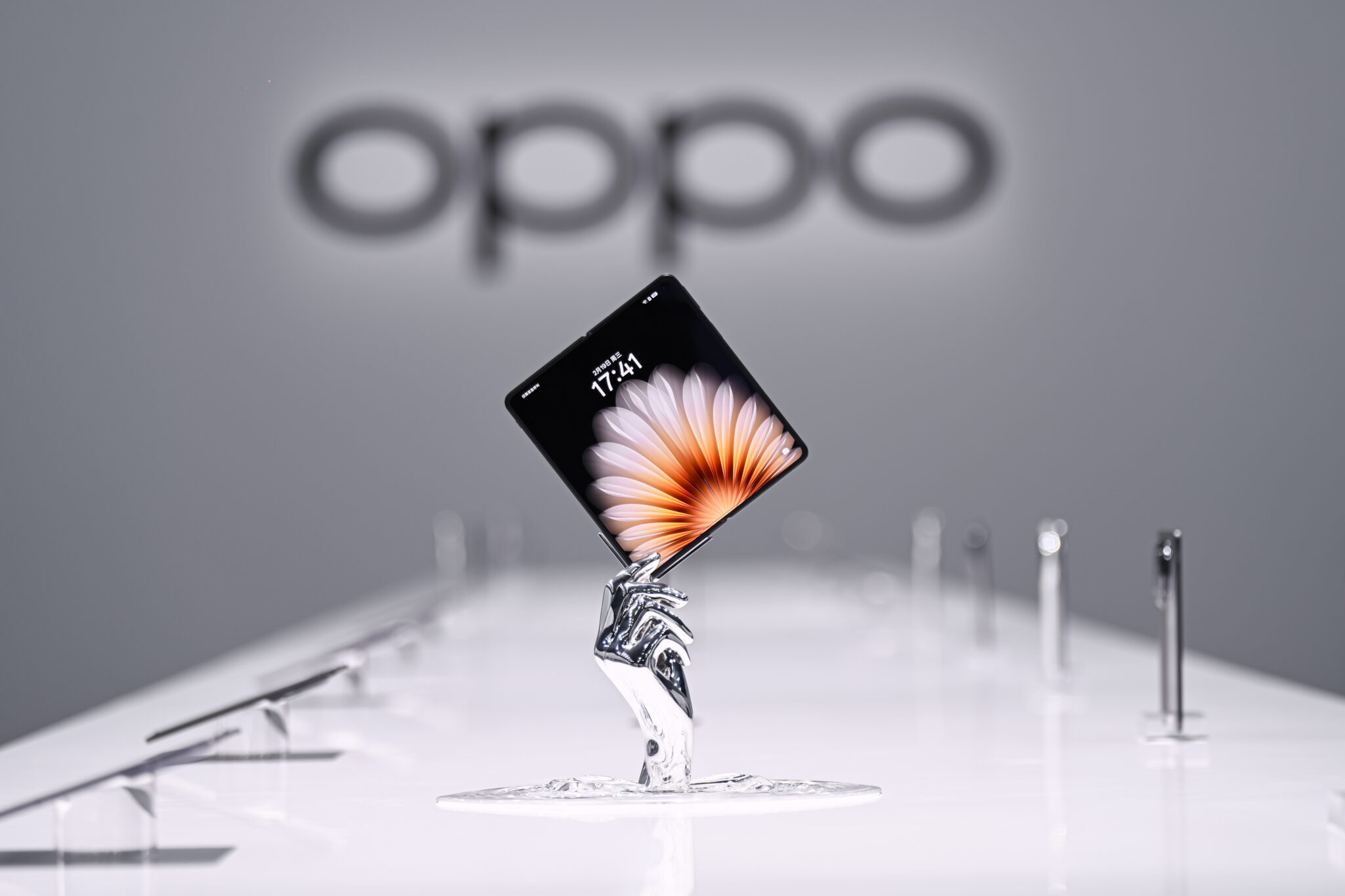 Chrome-finished metal display hand stand holding a foldable phone in a showroom
