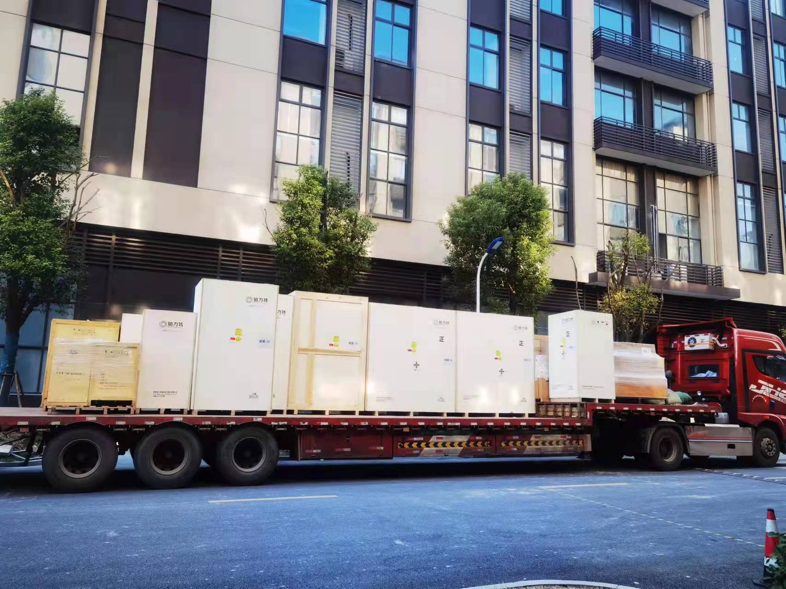 Red flatbed truck loaded with upright equipment crates — logistics context for metal AM programs