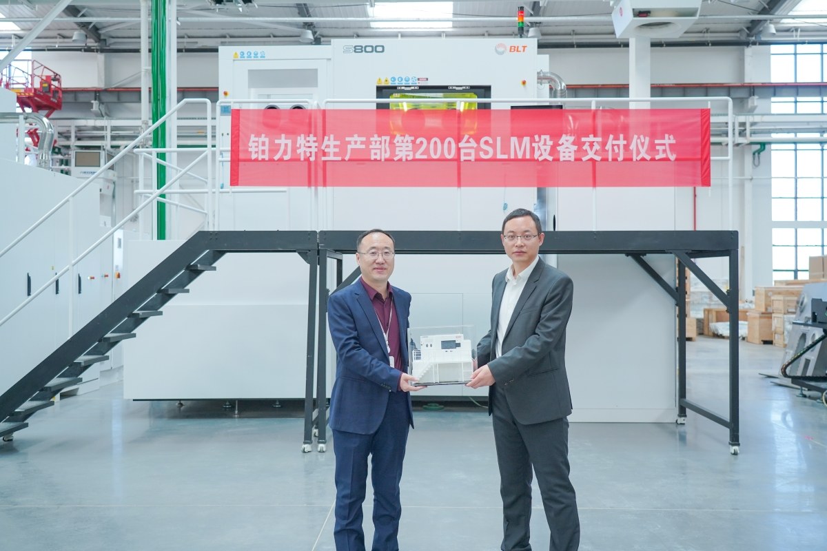 Factory delivery ceremony beside a large metal additive manufacturing system